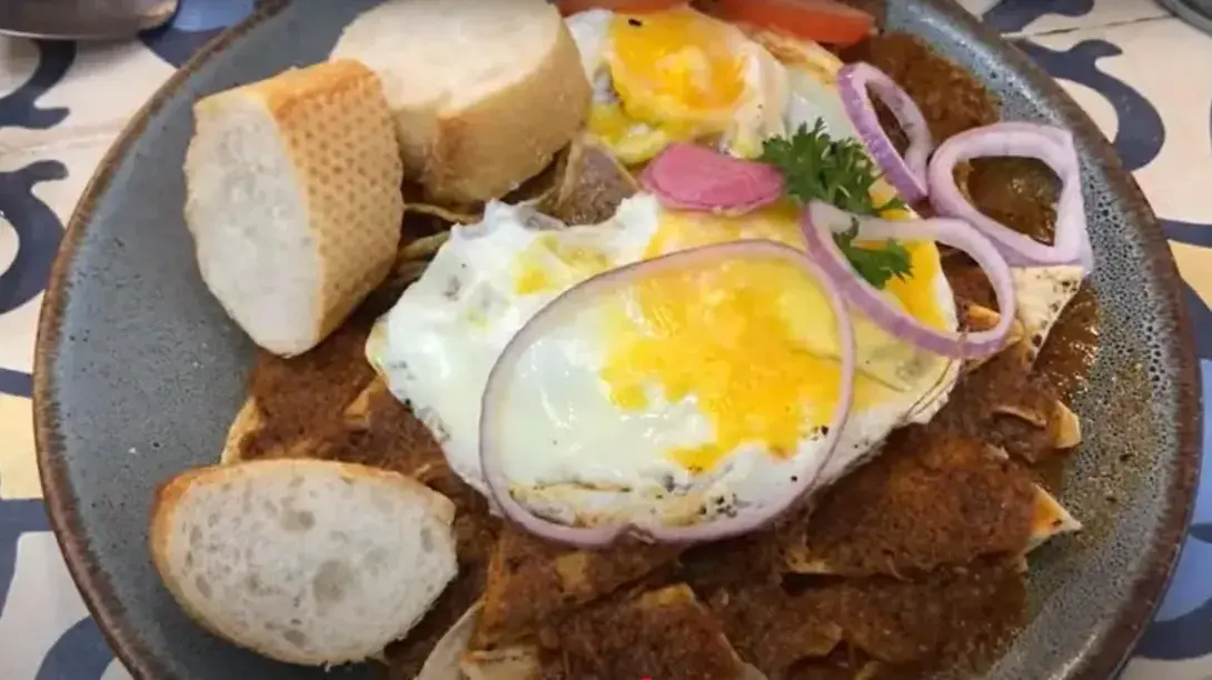 Plato de comida con huevo, pan, cebolla morada y salsas