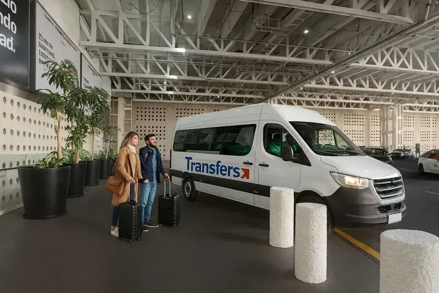 Pareja de viajeros esperando subir a una van de Transfers en la zona de ascenso y descenso de pasajeros en el aeropuerto Benito Juarez